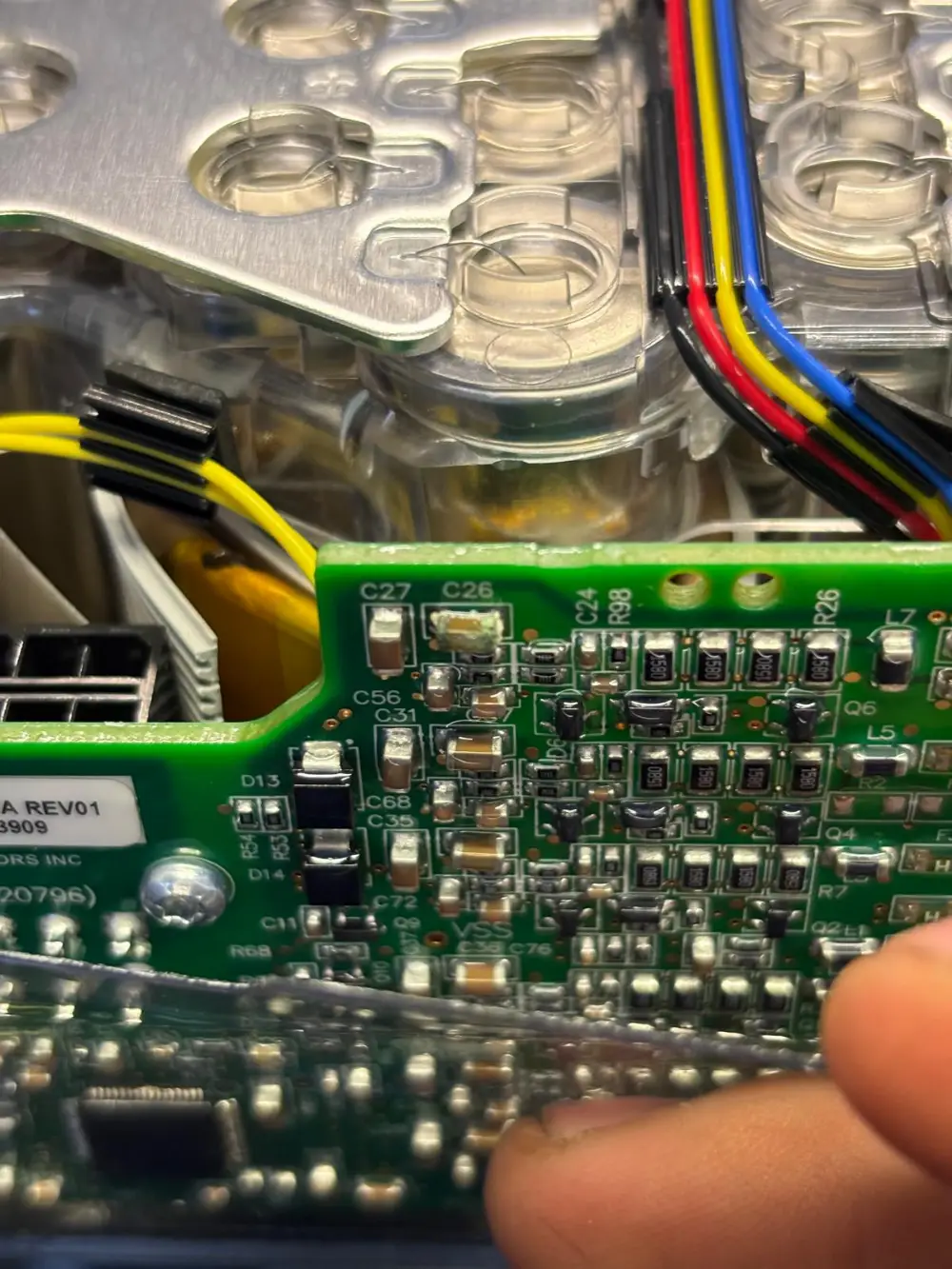 A battery monitoring board lifted off a module, cell tops and sense wires below it