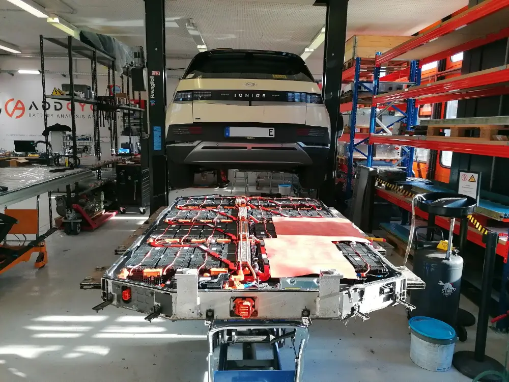 An Ioniq 5 on the lift with its pack out on a table below, modules exposed